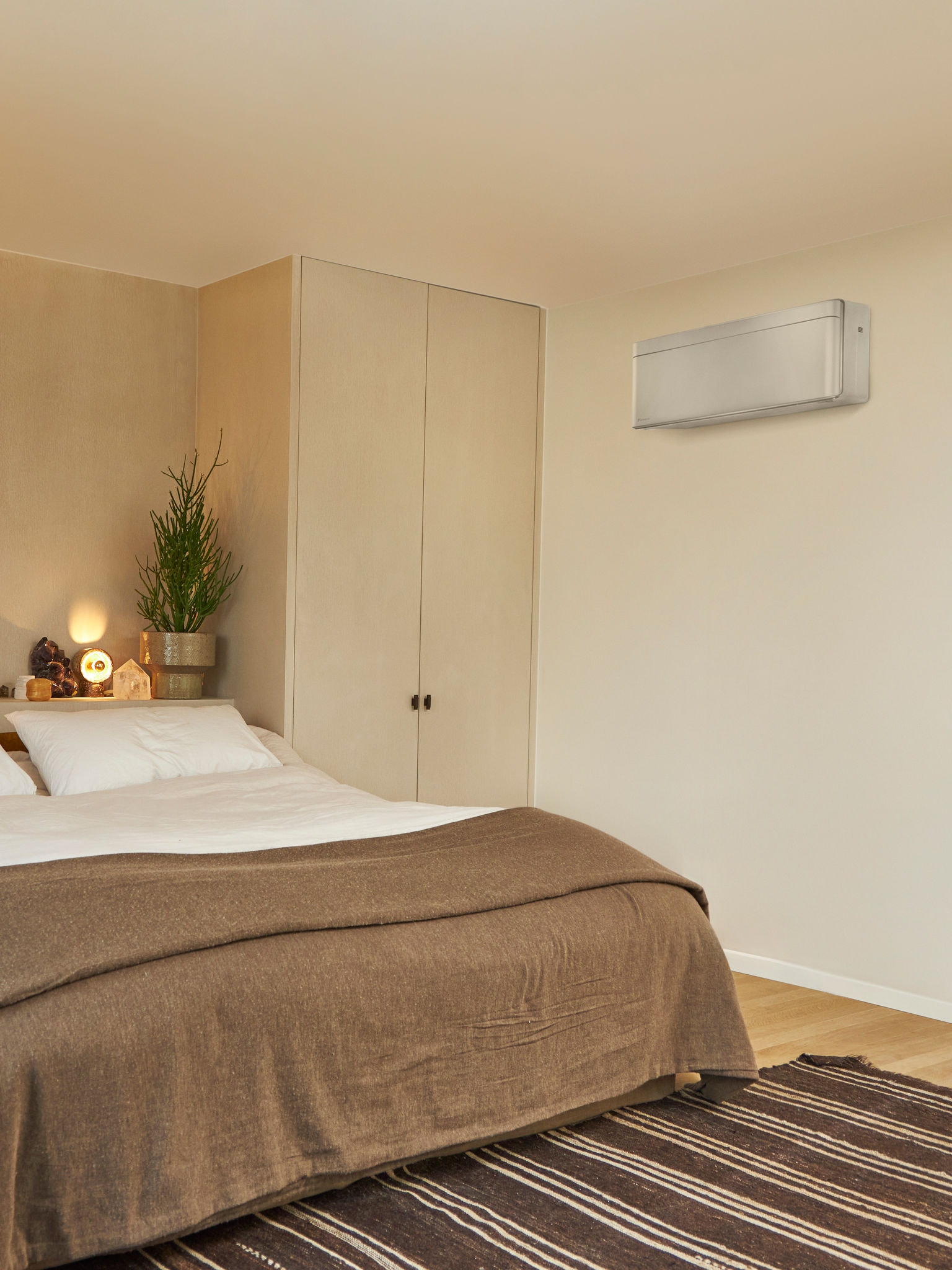 Schlafzimmer mit großem Bett und wandmontierter Klimalösung